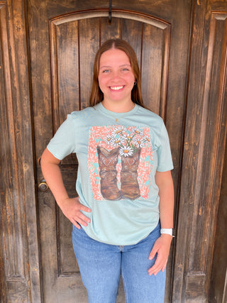 Daisy Boots Tee – Dusty Blue	Cowgirl boot tee with daisy details on a dusty blue background – feminine Western vibe