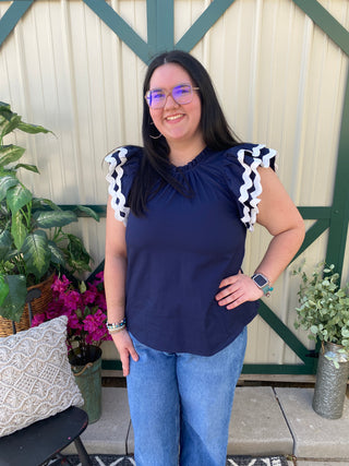 Navy Ruffle Sleeve Top	Navy blue ruffle sleeve blouse for women – gathered neckline and bold ric rac trim on shoulders