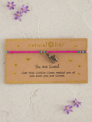 Necklace with 'natural life' branding on a beige card with flowers around