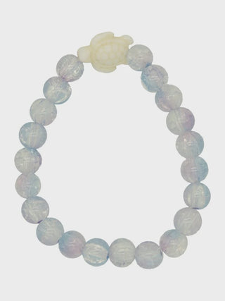 Opalite beaded bracelet with a white stone charm on a light gray background