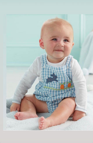 Baby wearing a checkered romper with a bunny design on a light blue background