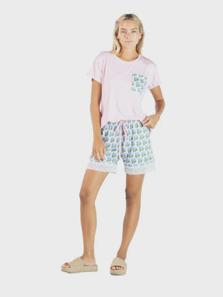 Woman wearing a pink t-shirt and patterned shorts on a white background