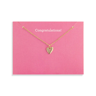 Gold heart necklace on a pink card with 'Congratulations!' text