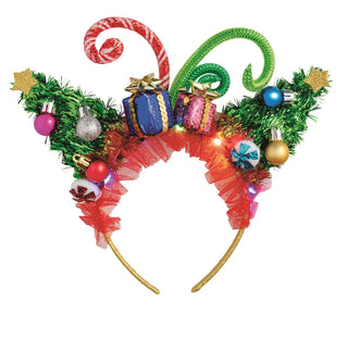 An over-the-top, festive Christmas headband featuring green tinsel Christmas trees topped with gold stars, a striped candy cane swirl, curled green mesh accents, miniature wrapped gifts, colorful ornaments, and a red ruffled base.