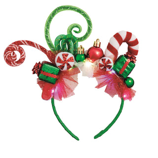 A whimsical Christmas headband featuring large red-and-white candy cane elements, curled green and red mesh extensions, green glittery gift boxes, round ornaments, peppermint candy accents, and a red tulle base.