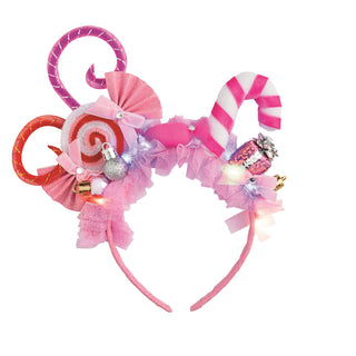 A candy-themed Christmas headband in a bright pink color scheme, featuring a plush pink-and-white striped candy cane, a large swirl lollipop, curled mesh extensions, a glittery pink gift box, satin bows, a silver ornament, and a pink ruffled tulle base.