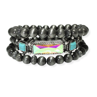 A three-strand Western-style stretch bracelet stack with burnished silver-tone beads, featuring a central bar set with a rectangular iridescent crystal flanked by turquoise stone accents, on a white background