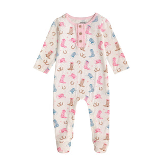 A white, long-sleeved infant footie sleeper featuring a Western pattern of cowboy boots, cowboy hats, and horseshoes in shades of pink, tan, and light blue.