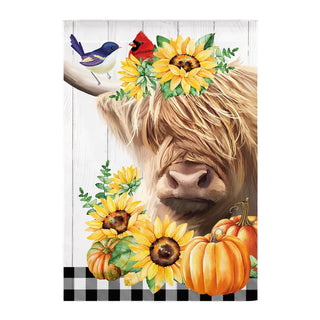 A decorative print or sign featuring a close-up illustration of a shaggy Highland cow face with yellow sunflowers and green leaves in its hair, plus small birds and pumpkins near the bottom, set against a white wood-plank background with a black-and-white checkered strip at the bottom.