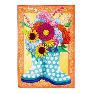 Decorative garden flag with a polka dot rain boot filled with colorful flowers on an orange background.
