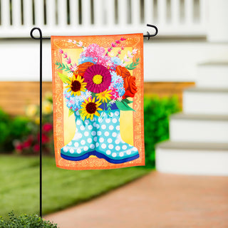 Decorative garden flag with a boot and flowers on a flagpole in front of a house.