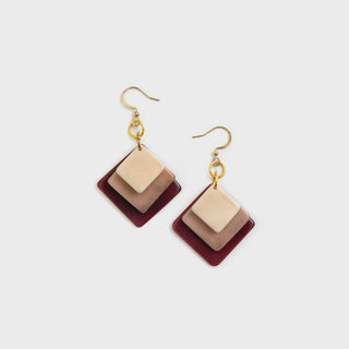 Pair of square-shaped earrings with gold hooks on a light gray background
