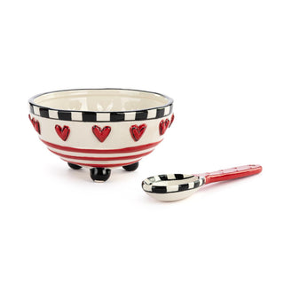 Ceramic bowl with red heart designs and a matching spoon on a white background