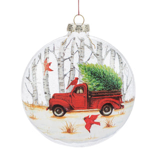 Christmas ornament with a red truck carrying a tree and birch trees in the background.