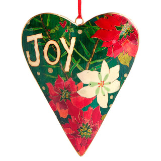 A heart-shaped wooden Christmas ornament featuring a festive design with the word 'Joy' in raised beige letters, red and white poinsettias, green holly leaves, and a red hanging loop on a white background.