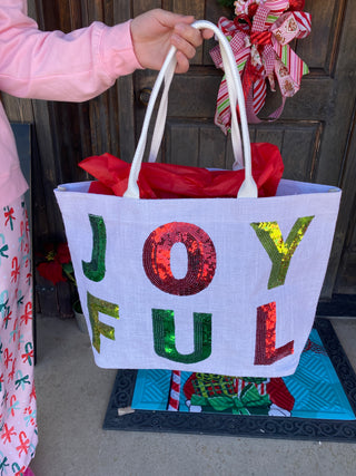 Decorative bag with colorful letters held by a person in front of a door.