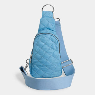 Blue quilted sling bag on a light gray background
