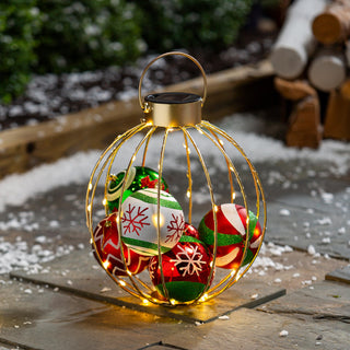Bring extra sparkle to your holiday décor with our festive Solar Christmas Ornament Lantern. Filled with colorful ornaments and wrapped in warm white LED lights, this golden-wire lantern 