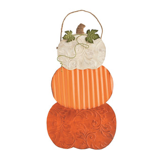 A decorative stacked autumn pumpkin wall hanging with three tiers: a white embossed top section with green leaves and a small brown stem, an orange striped middle section, and a textured orange bottom section, suspended by a twine handle on a white background.