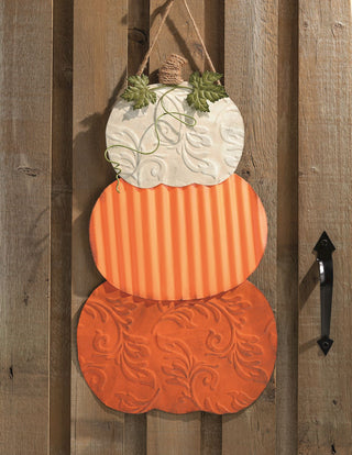 Decorative pumpkin wall hanging with embossed patterns on a wooden door.