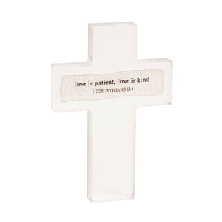 White cross with 'love is patient, love is kind' text on a white background