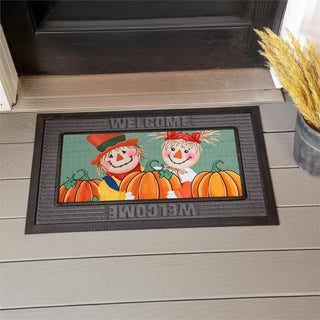 Decorative doormat with scarecrows and pumpkins on a wooden floor.