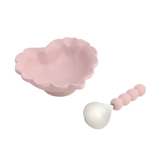 A light pink ceramic bowl that comes with a decorative spoon 