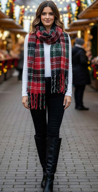  a woman modeling a red, green, and black plaid fringed scarf in an outdoor Christmas market setting