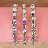 Three silver bracelets featuring iridescent, multi-colored crystals in oval, marquise, and round shapes.