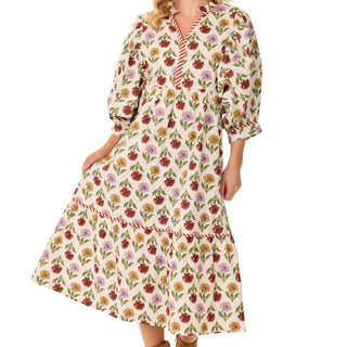 A cream-colored, tiered maxi dress with a colorful all-over floral pattern, featuring puff sleeves and a striped V-neckline border.