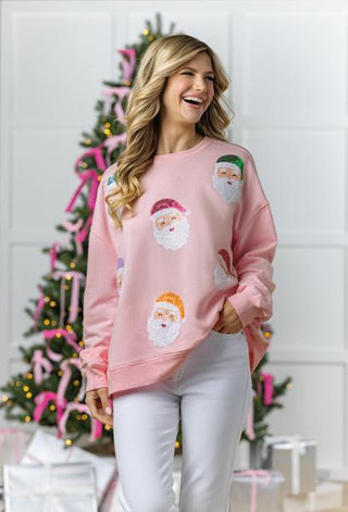 A pink sweater with sequin Santa Claus designs