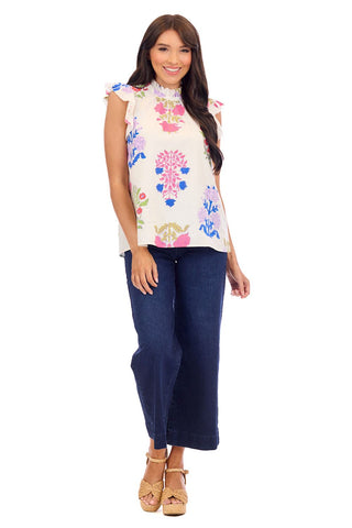 Woman wearing a colorful floral top and blue jeans on a white background
