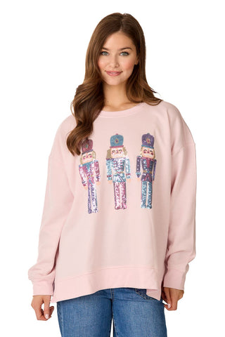 An adult's light pink crewneck sweatshirt featuring three pastel, sequined nutcracker graphics across the front.