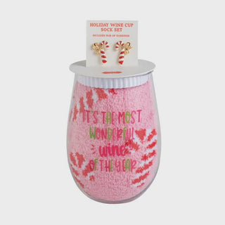 Stemless holiday wine glass paired with fuzzy candy cane socks and candy cane earrings