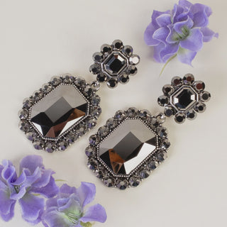 Gunmetal-toned statement earrings featuring large emerald-cut black crystals surrounded by a faceted crystal halo.