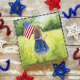 Decorative photo with a girl holding an American flag on a wooden surface with festive decorations.