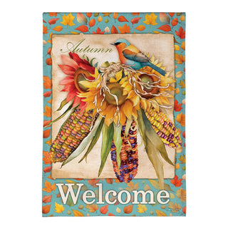 A decorative autumn-themed garden sign or plaque featuring a bird perched on sunflowers with corn ears, surrounded by colorful fall leaves and the word 'Welcome' at the bottom.