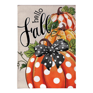 A rectangular decorative sign or print featuring the words “hello fall” in black script over illustrated orange pumpkins with white polka dots, striped orange-and-white pumpkins, green leaves, and a black ribbon with white polka dots on a light beige background.