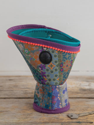 Colorful fabric funnel-shaped container on a wooden surface with a white background