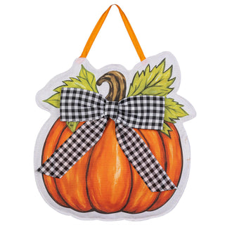 A decorative autumn pumpkin wall hanging with an orange fabric body, printed stem, green leaves, and a black-and-white gingham bow, shown on a plain white background.