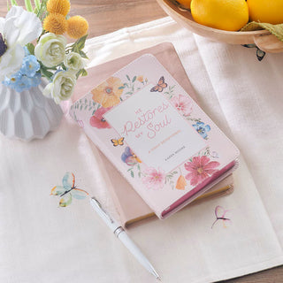 Floral notebook with pen on a table with flowers and fruit