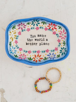 Decorative tray with floral border and motivational quote, accompanied by a beaded bracelet on a white background.