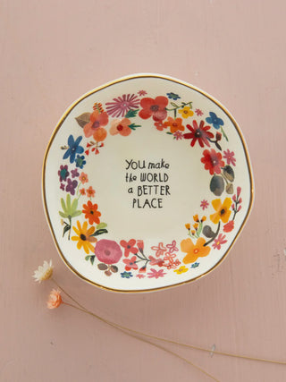 Decorative dish with floral design and text on a pink background