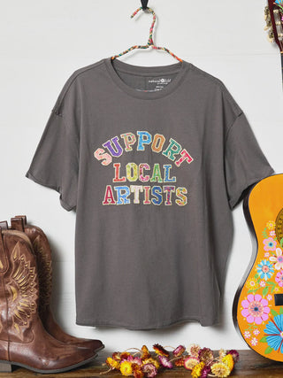 Gray t-shirt with 'Support Local Artists' text, cowboy boots, and a colorful guitar on a white background