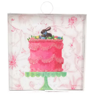 A square decorative plaque featuring an illustration of a bright pink ruffled cake topped with a chocolate bunny and small colorful eggs, set on a green cake stand against a light pink floral background.