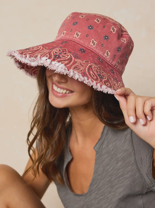 Woman wearing a red patterned sun hat against a beige background