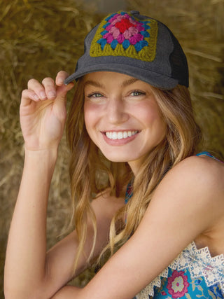 Woman wearing a colorful crochet cap against a hay background
