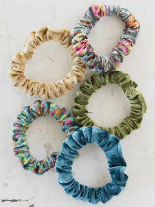 five velvet scrunchies on a white background