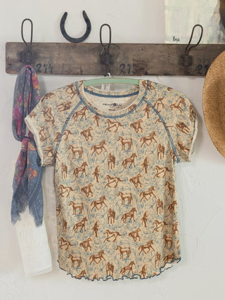  t-shirt with horse pattern hanging on a wooden hook rack.