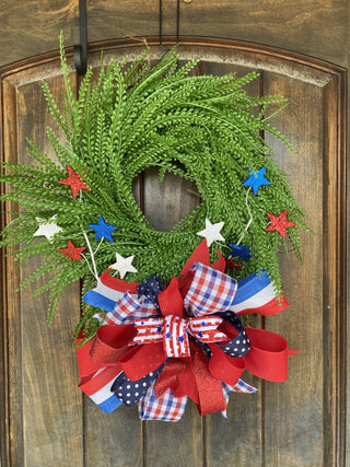 Green wreath with red, white, and blue decorations on a wooden door